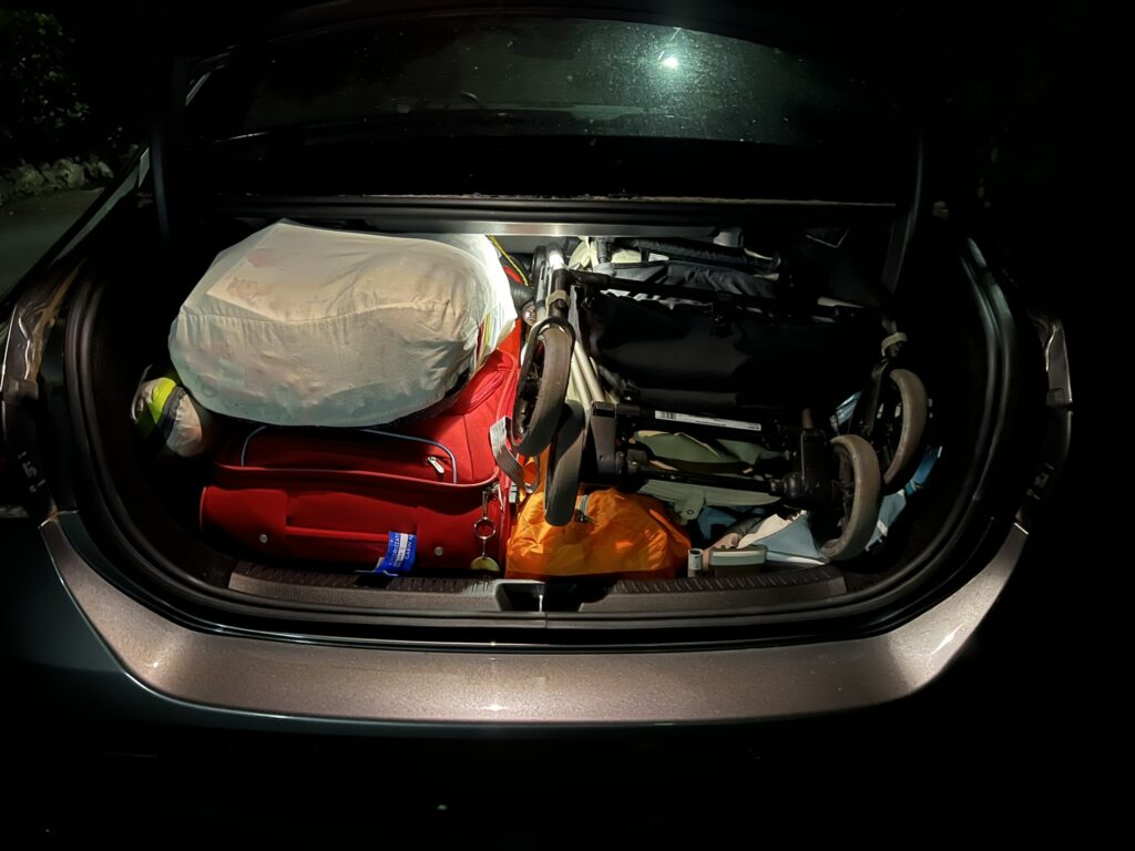 Bagagliaio auto a noleggio organizzato con valigie e passeggino