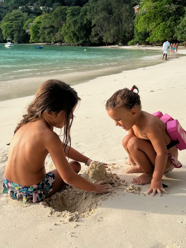 Bambini che giocano sul bagnasciuga di una spiaggia calma a Mahé