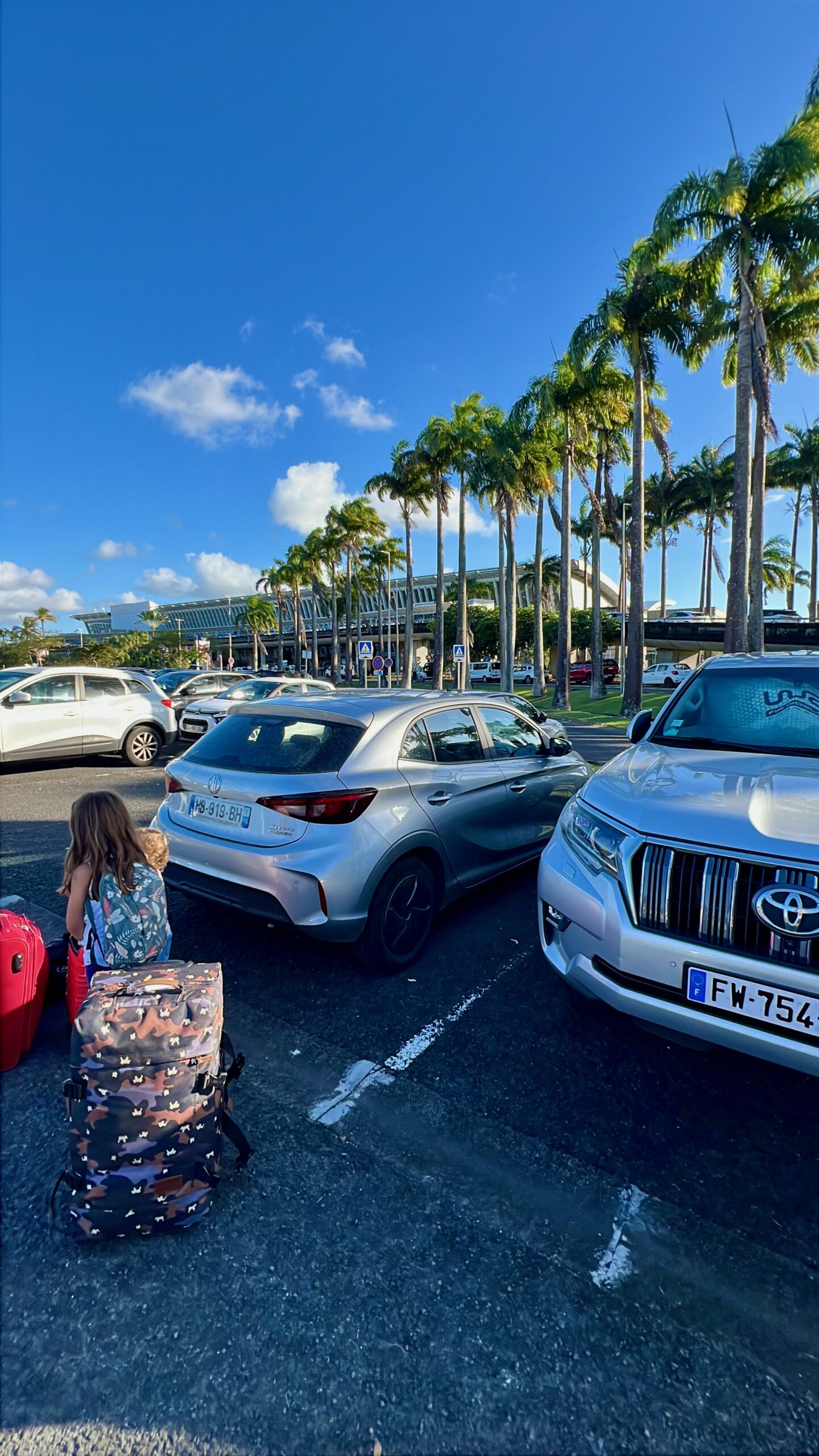 Luggage and rental car at Guadeloupe airport with kids